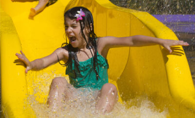 Children splashing down the yellow slide at Dippy's Splash Zone
