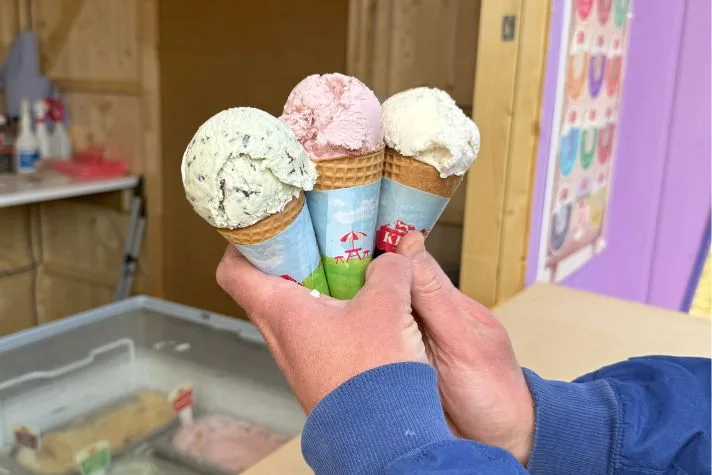 Three Kelly’s ice cream cones held up at the parlour counter