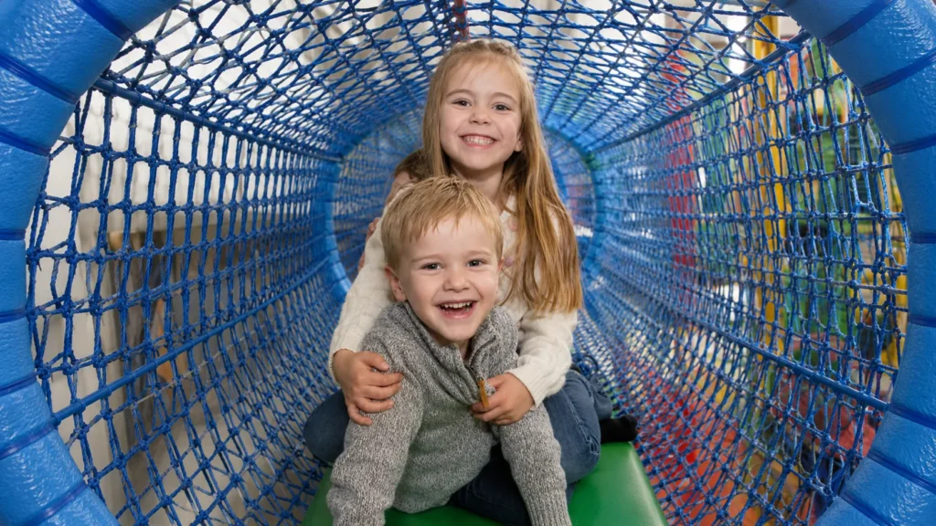 Two children playing in the indoor soft-play net tunnel