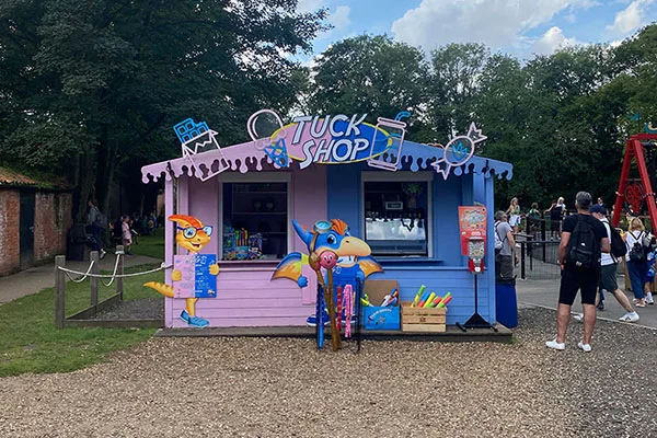 The pink and blue Tuck Shop kiosk with Dippy character cut-outs outside